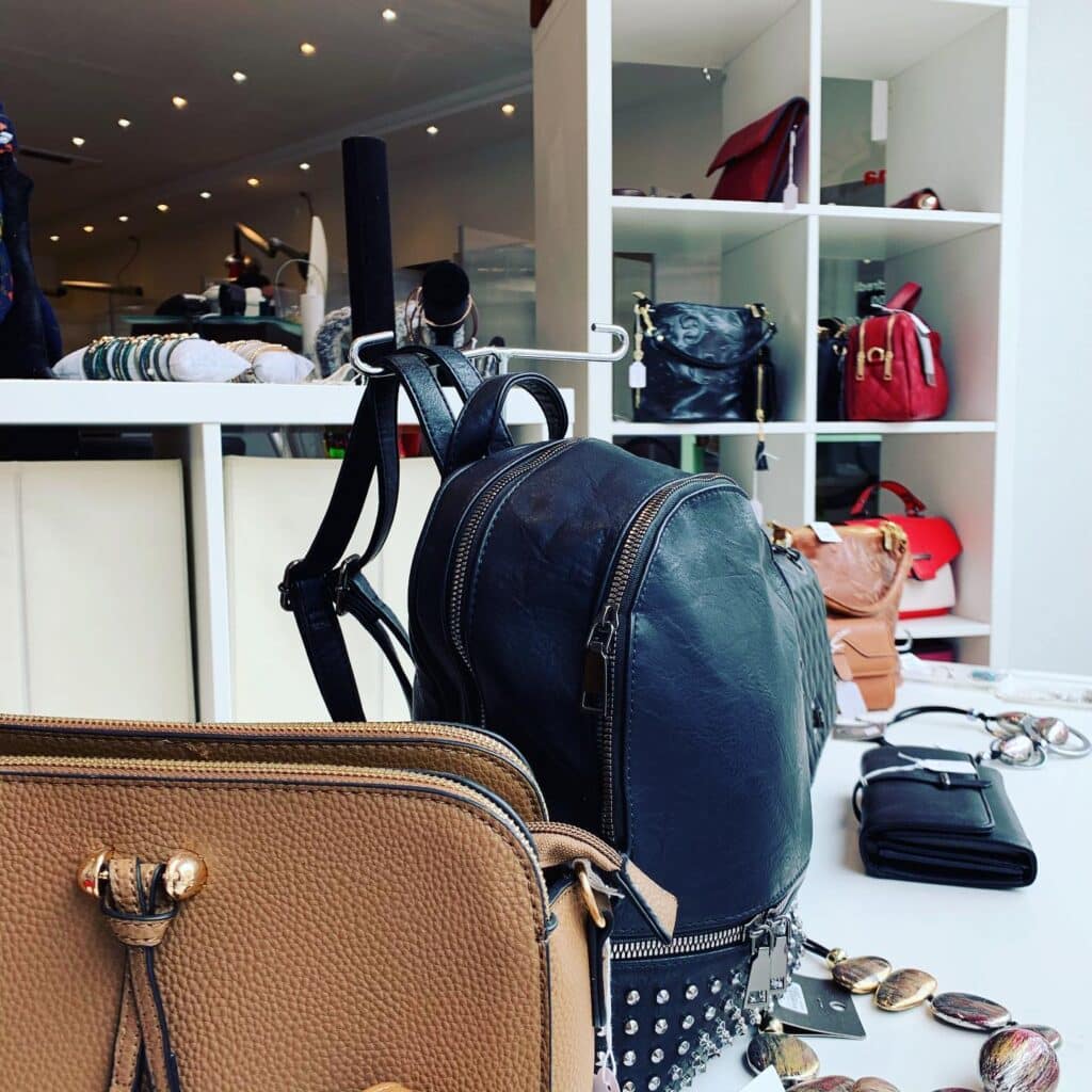 Sacs à Main et Accessoires de Mode en Boutique de Luxe Sac à dos noir en cuir, sac à main beige et accessoires de mode exposés dans une boutique de maroquinerie élégante.