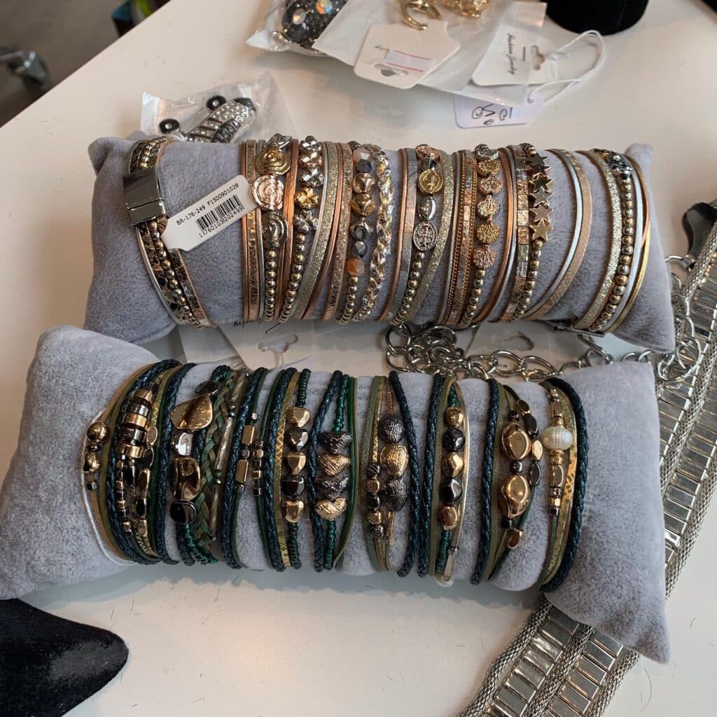 Bracelets Multi-Rangs Tendance : Dorés, Argentés et Verts Bracelets multi-rangs fantaisie BR-176-249 dorés, argentés et verts avec perles et breloques sur coussins gris.